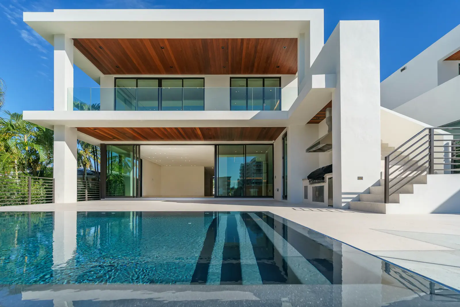 Villa blanche à plafonds de bois, piscine en longueur au premier plan