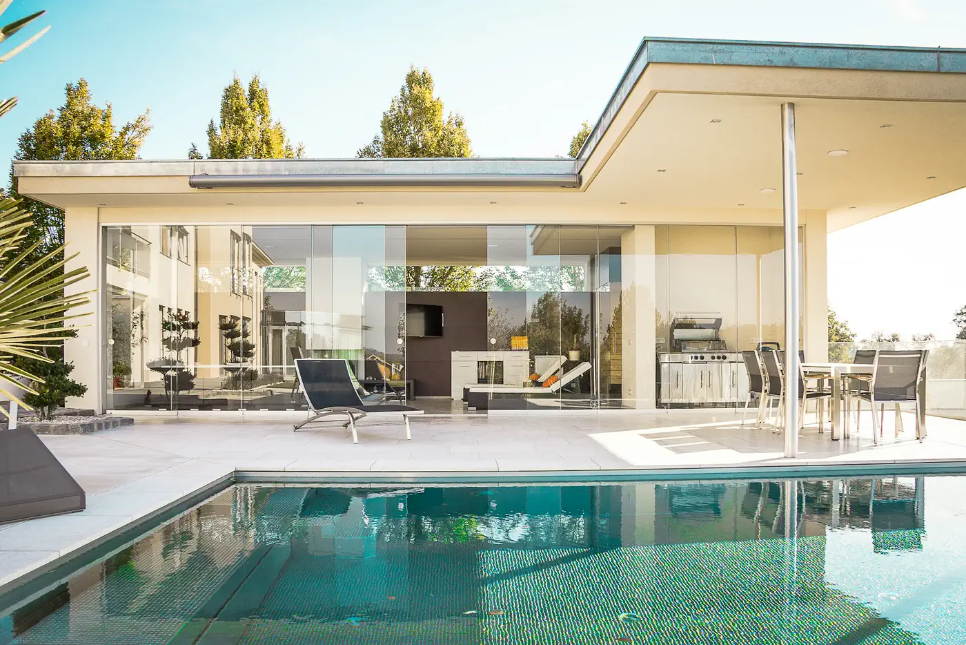 Maison contemporaine ouverte sur une piscine, grandes baies vitrées et terrasse